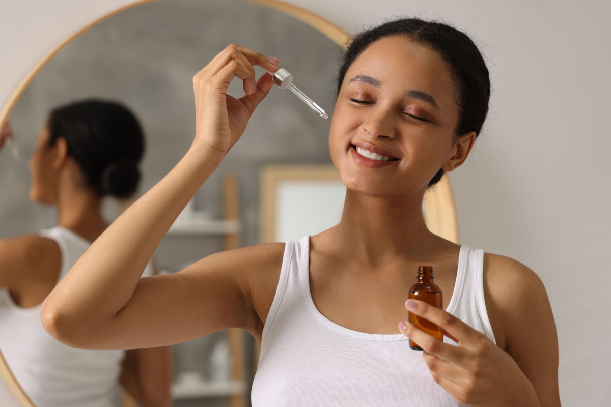 Mulher realizando cuidados faciais em uma rotina de skincare, com aplicação suave de produto no rosto.