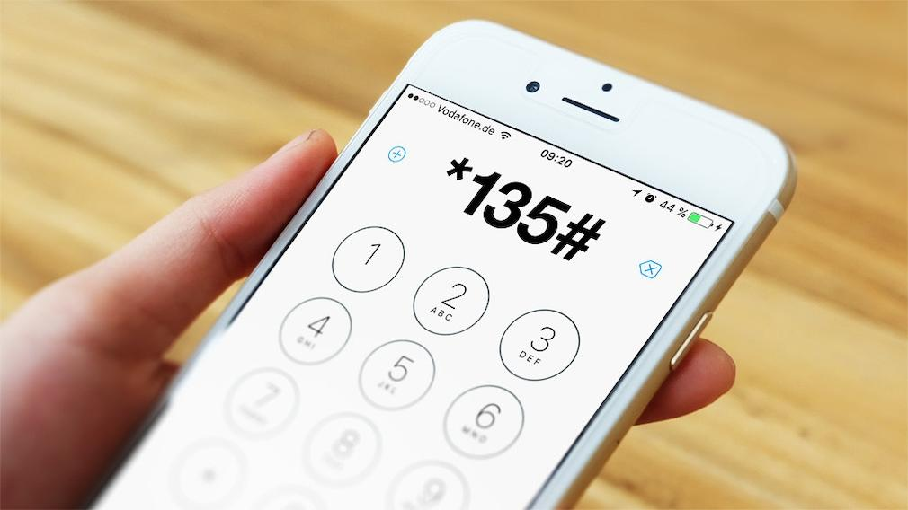Usuário consulta um código no teclado telefônico para verificar configurações da linha.