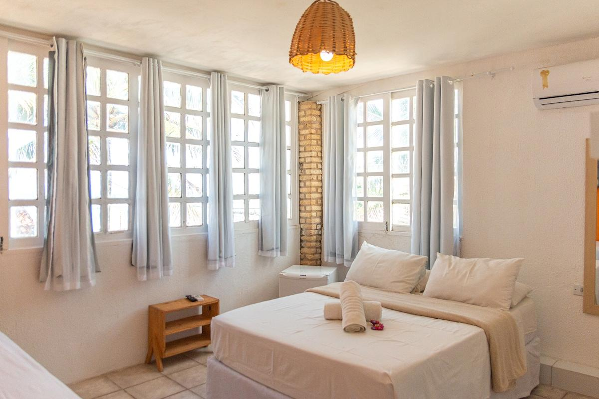 Quarto de pousada simples, organizado e bem iluminado.